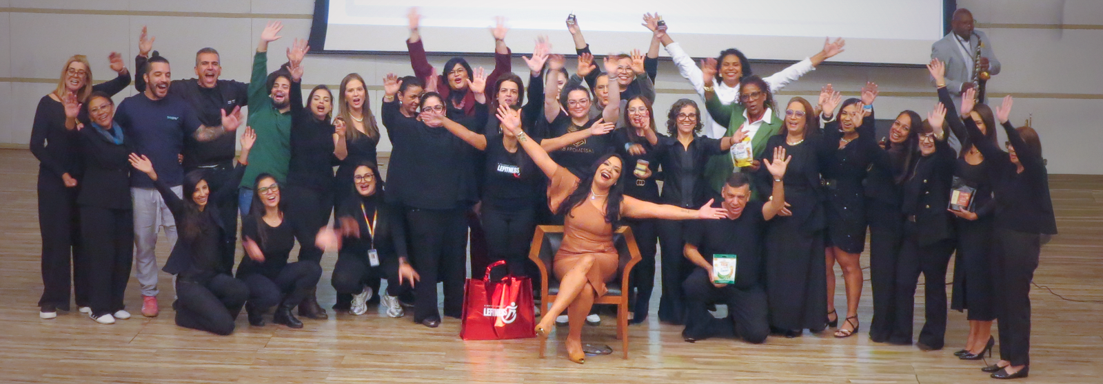 Participantes e parceiros celebram no palco do encontro Mulheres que Avançam, em maio de 2026